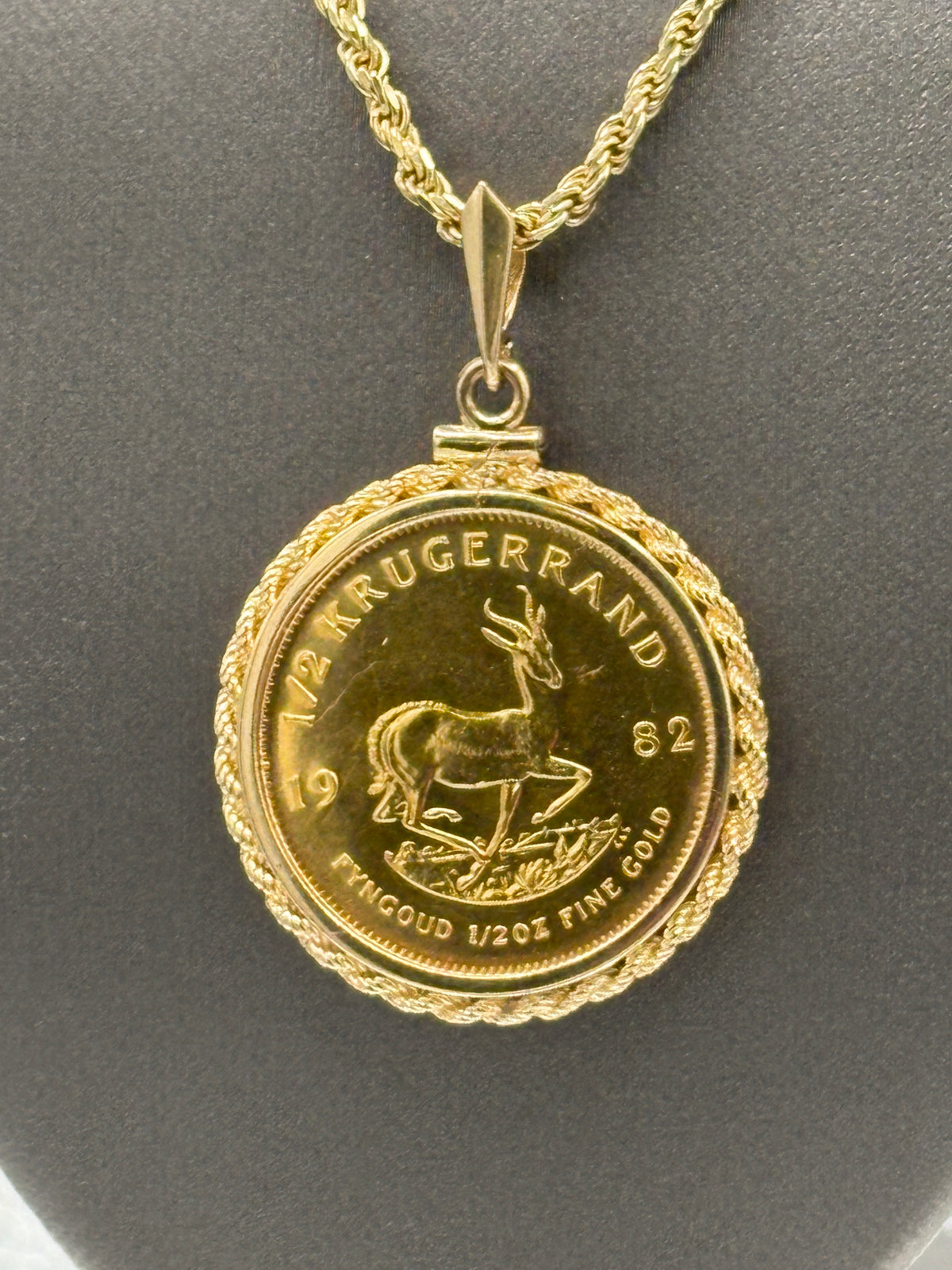 Gold necklace with a coin pendant on a dark background