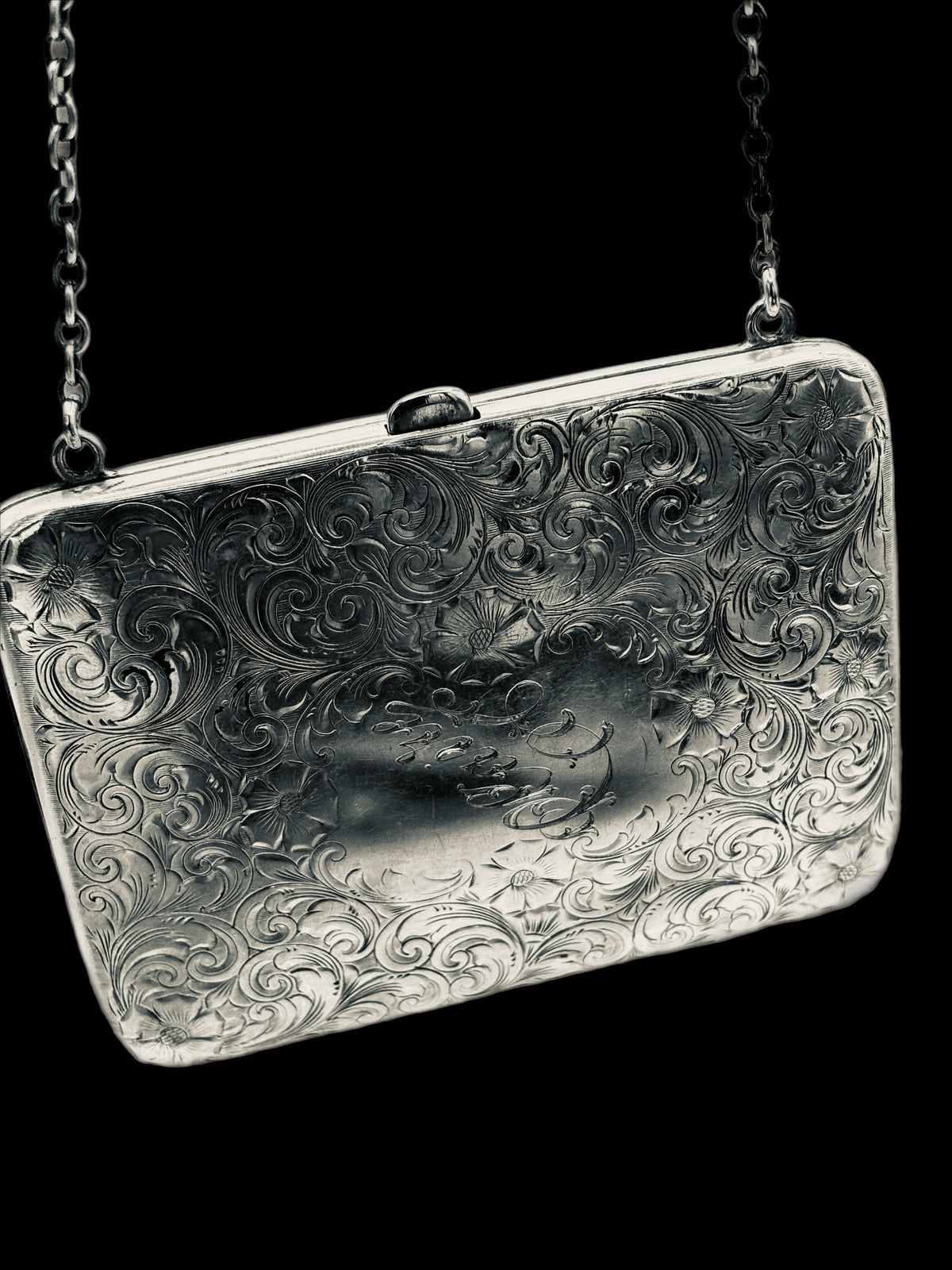 Silver embossed clutch bag with chain strap on a black background