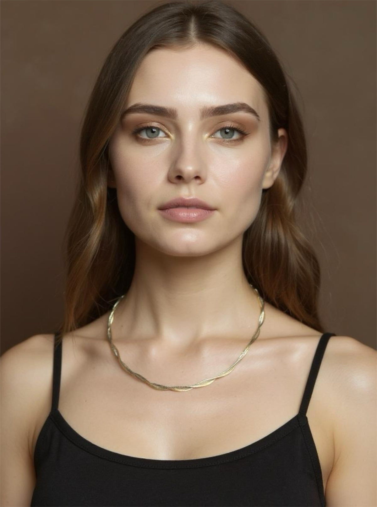 Woman wearing a gold necklace against a brown background