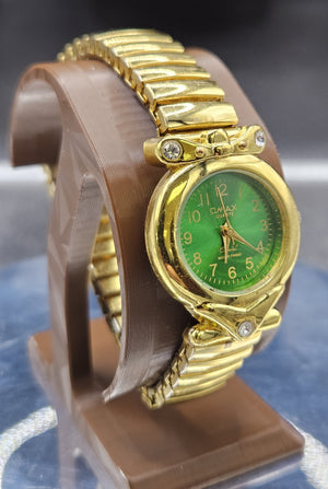Vintage Womens gold-tone wristwatch features a stretch band and green dial