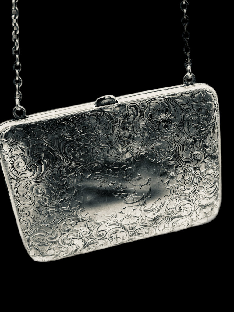 Silver embossed clutch bag with chain strap on a black background