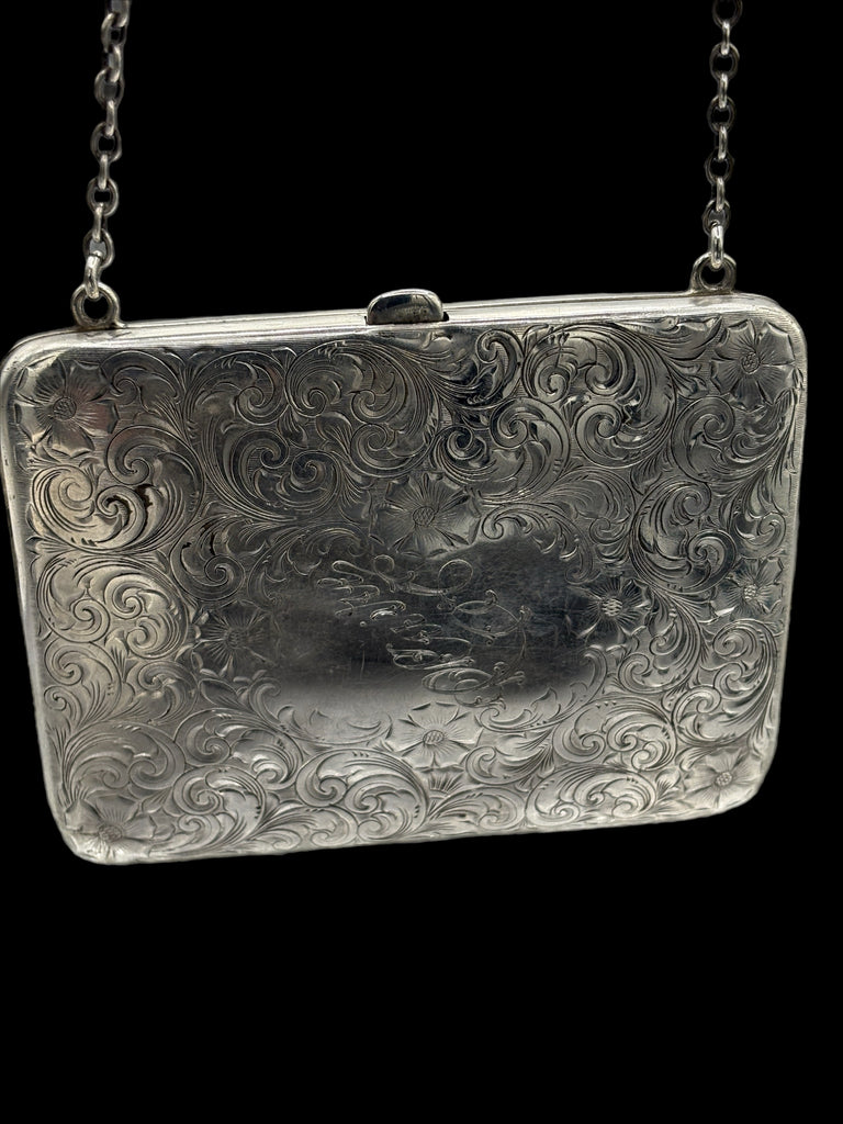 Silver embossed clutch bag with chain strap on a black background