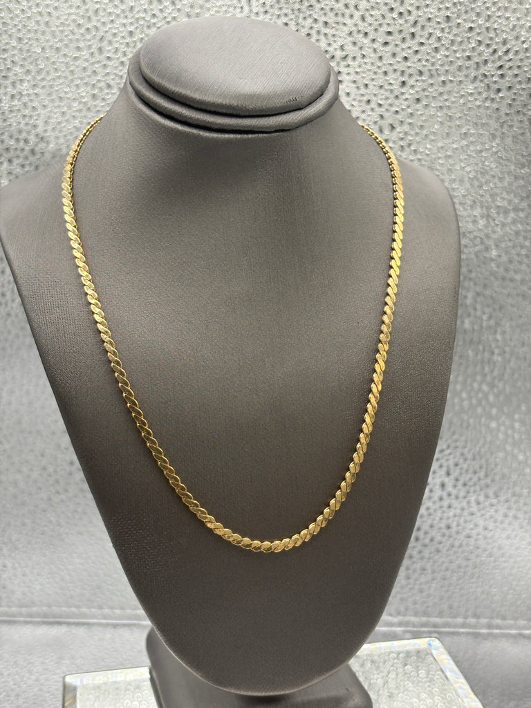 Gold chain on a gray mannequin against a neutral background