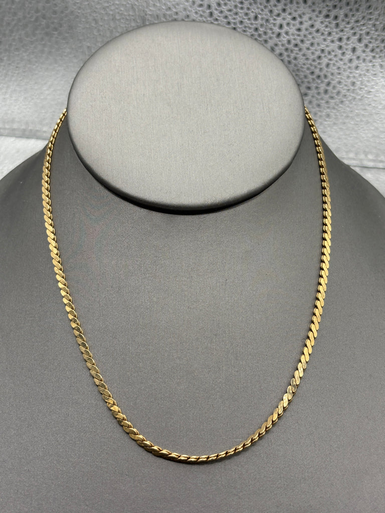Gold chain on a mannequin bust against a gray background
