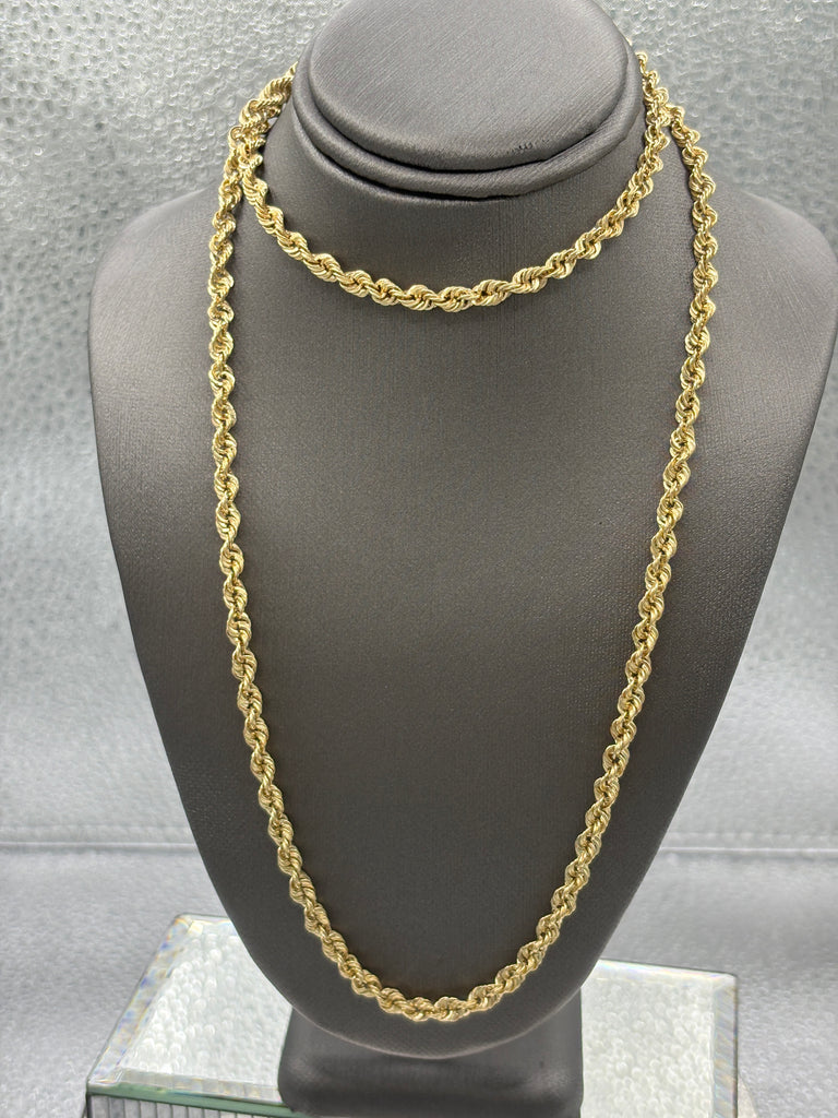 Gold chain necklace on a gray mannequin bust against a neutral background