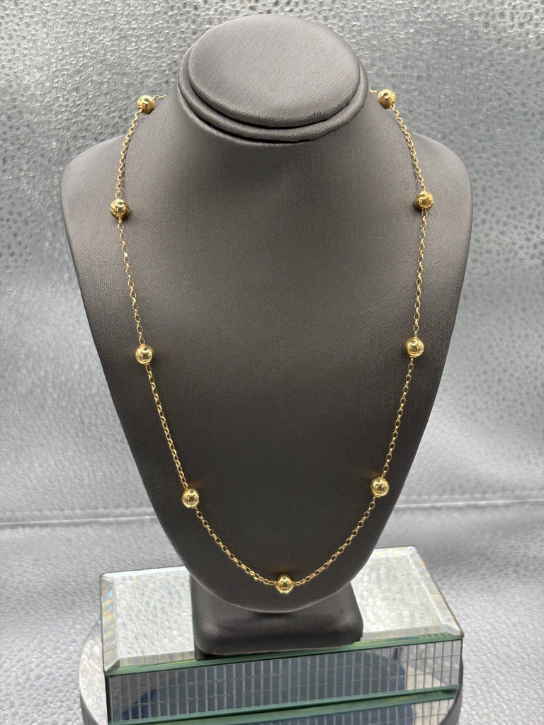 Gold necklace on a gray mannequin bust against a neutral background