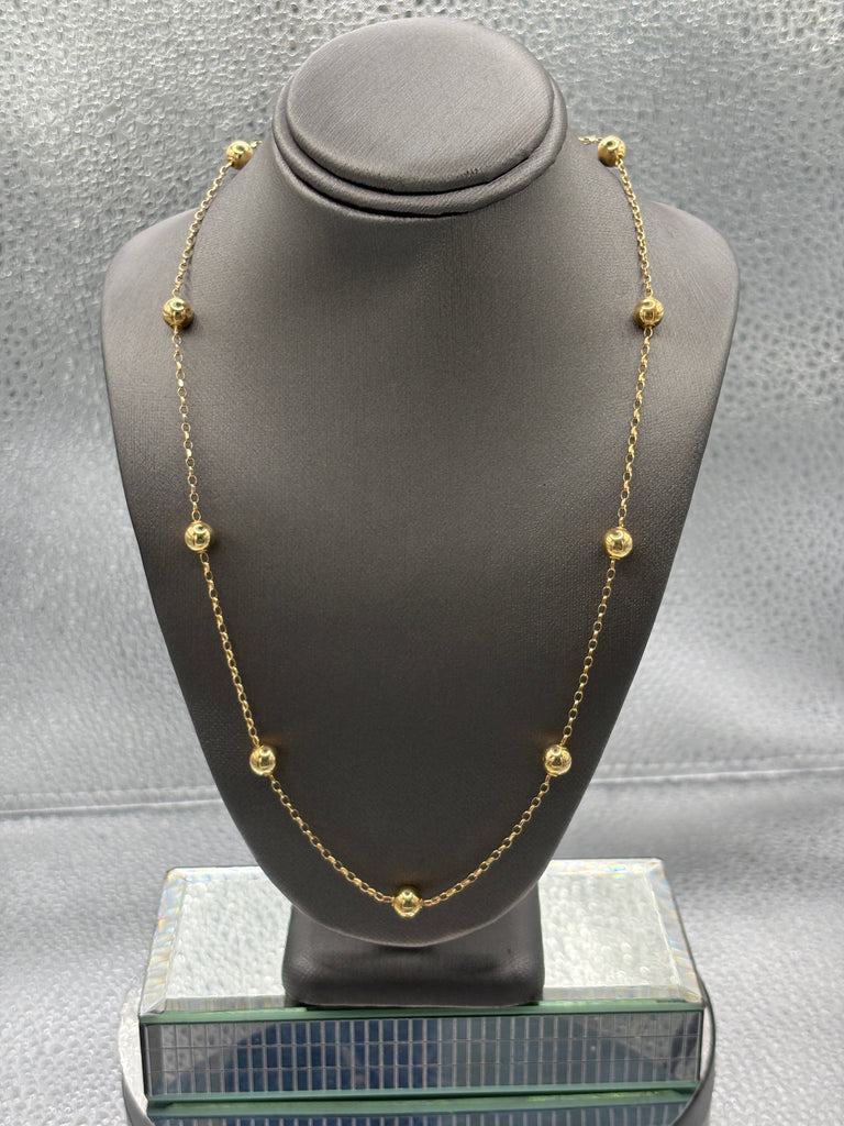 Gold necklace on a gray mannequin bust against a neutral background