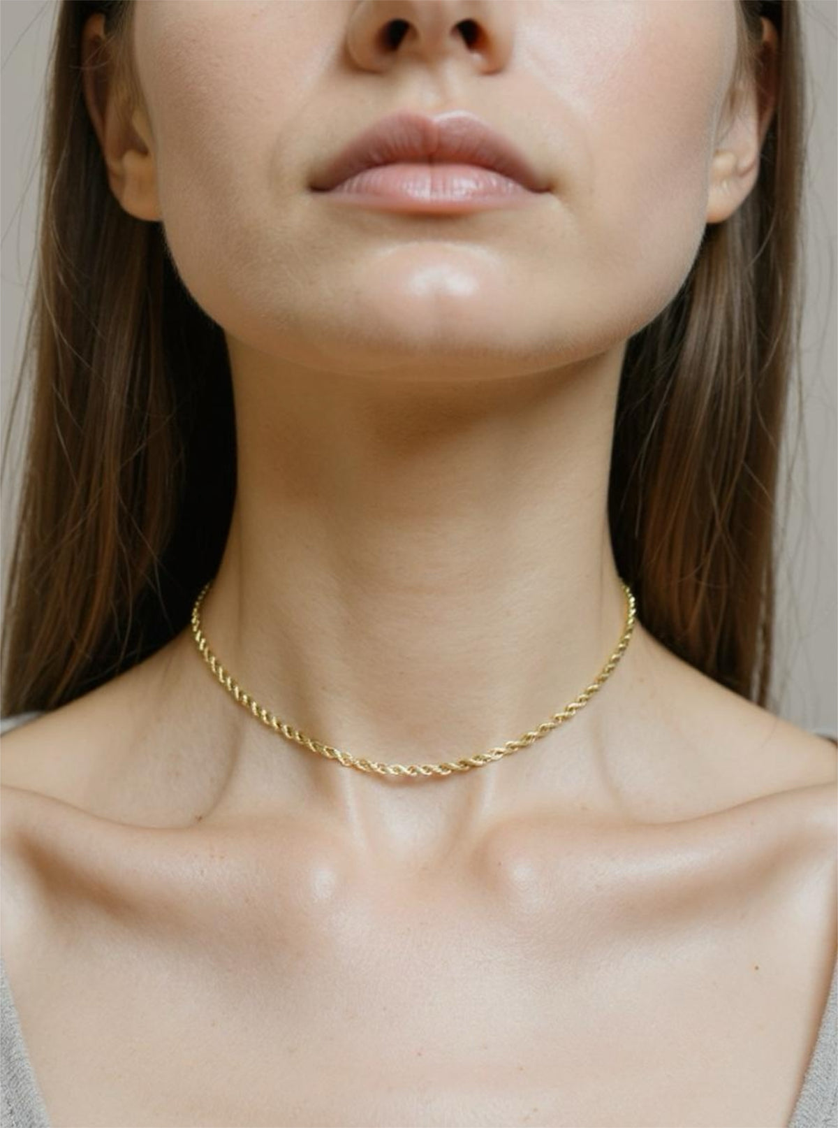 Gold necklace on a person with a neutral background