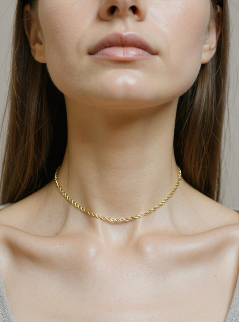 Gold necklace on a person with a neutral background
