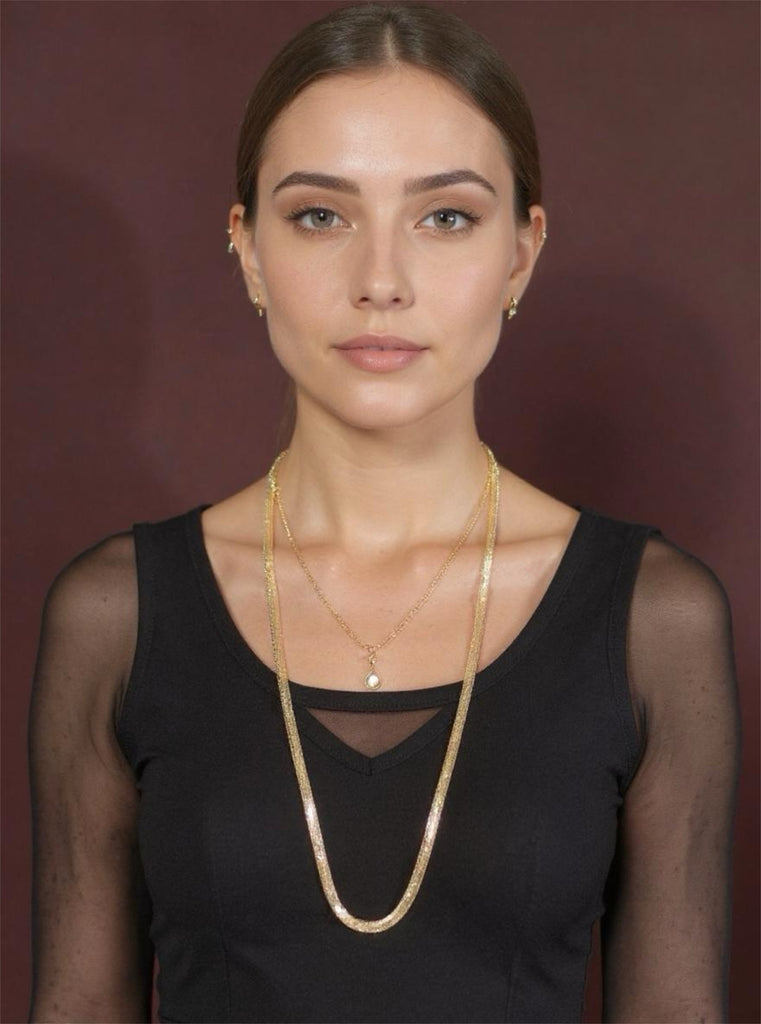 Woman wearing a gold necklace against a dark background