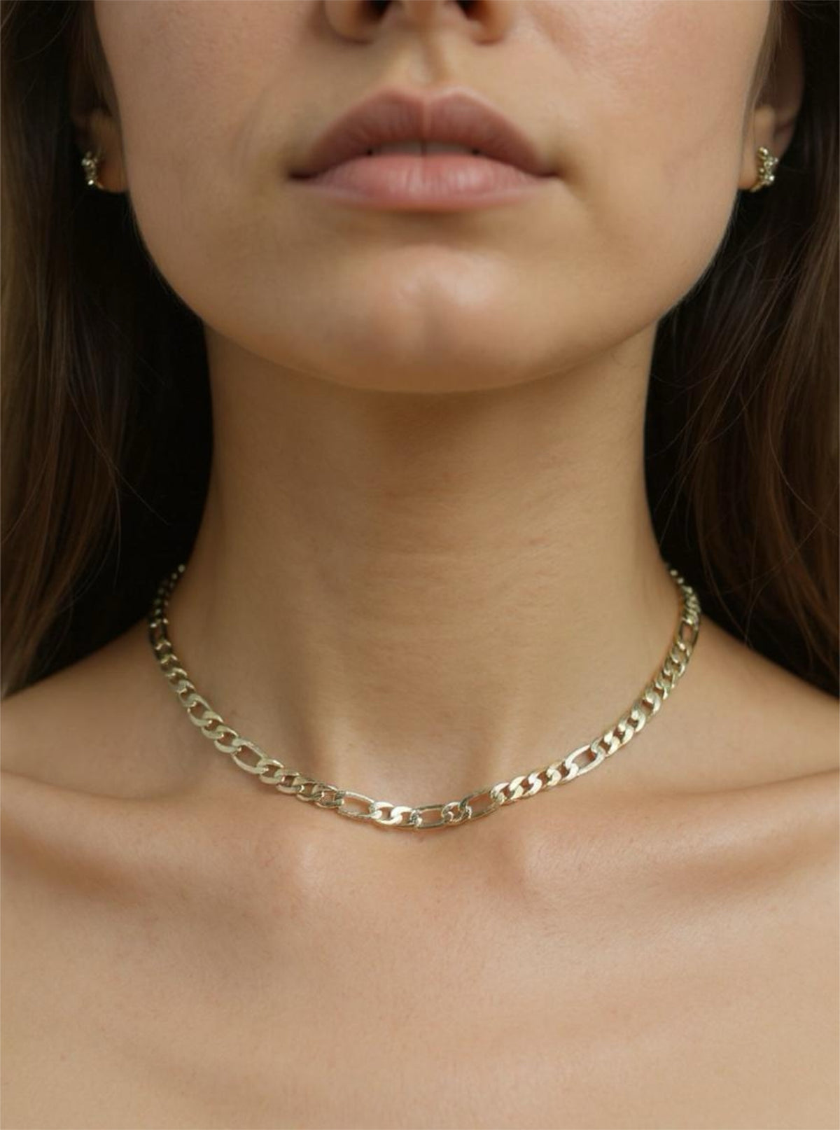 Close-up of a person wearing a gold chain necklace with a blurred background