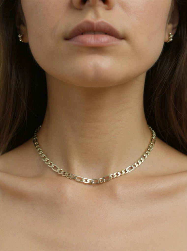 Close-up of a person wearing a gold chain necklace with a blurred background