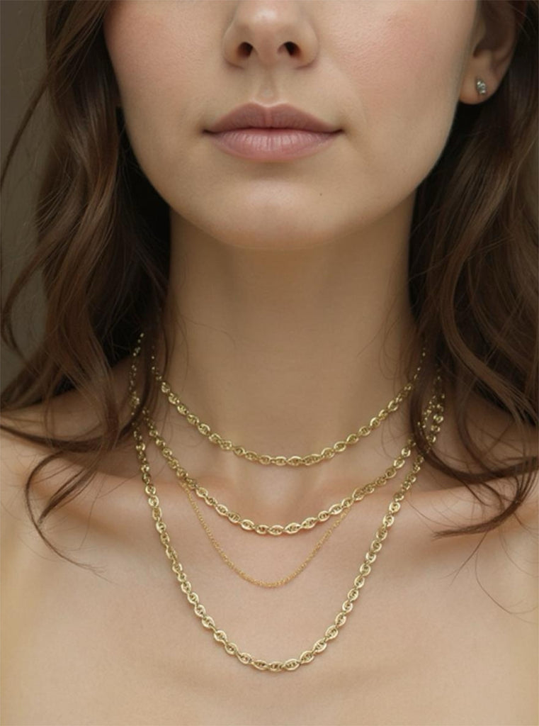 Close-up of a woman wearing gold necklaces with a neutral background