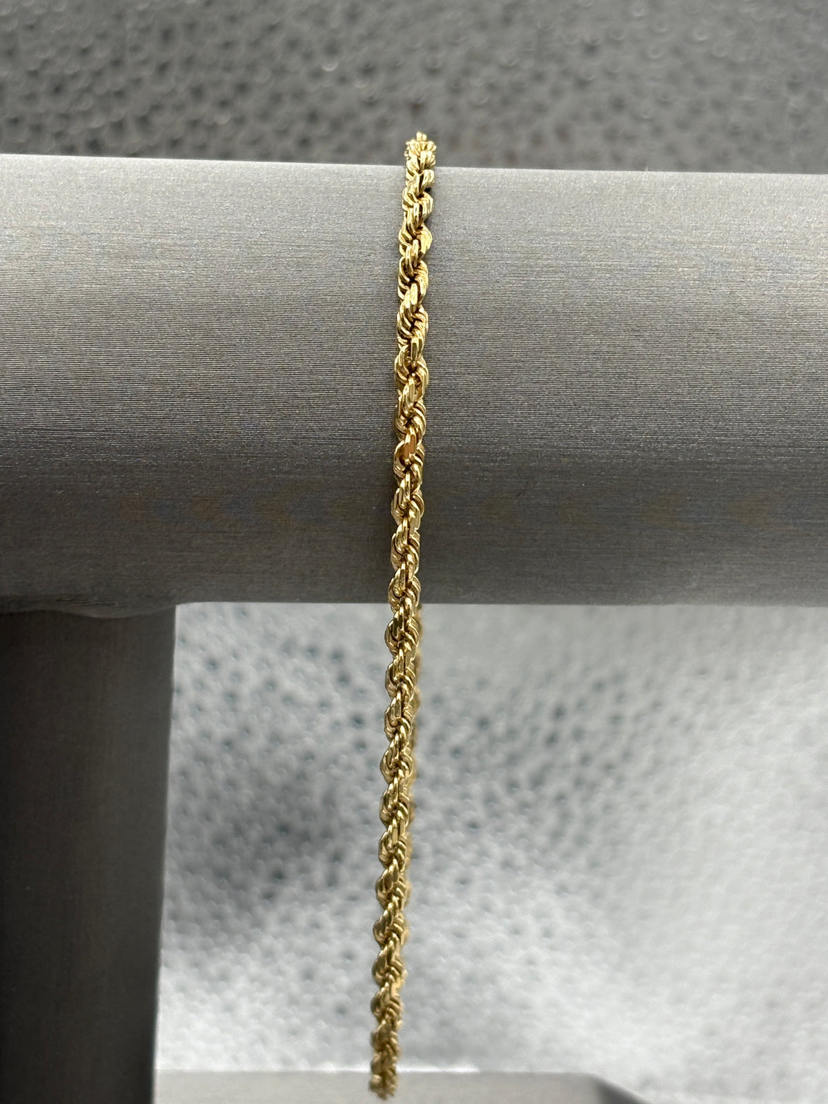 Gold rope chain bracelet on a gray surface